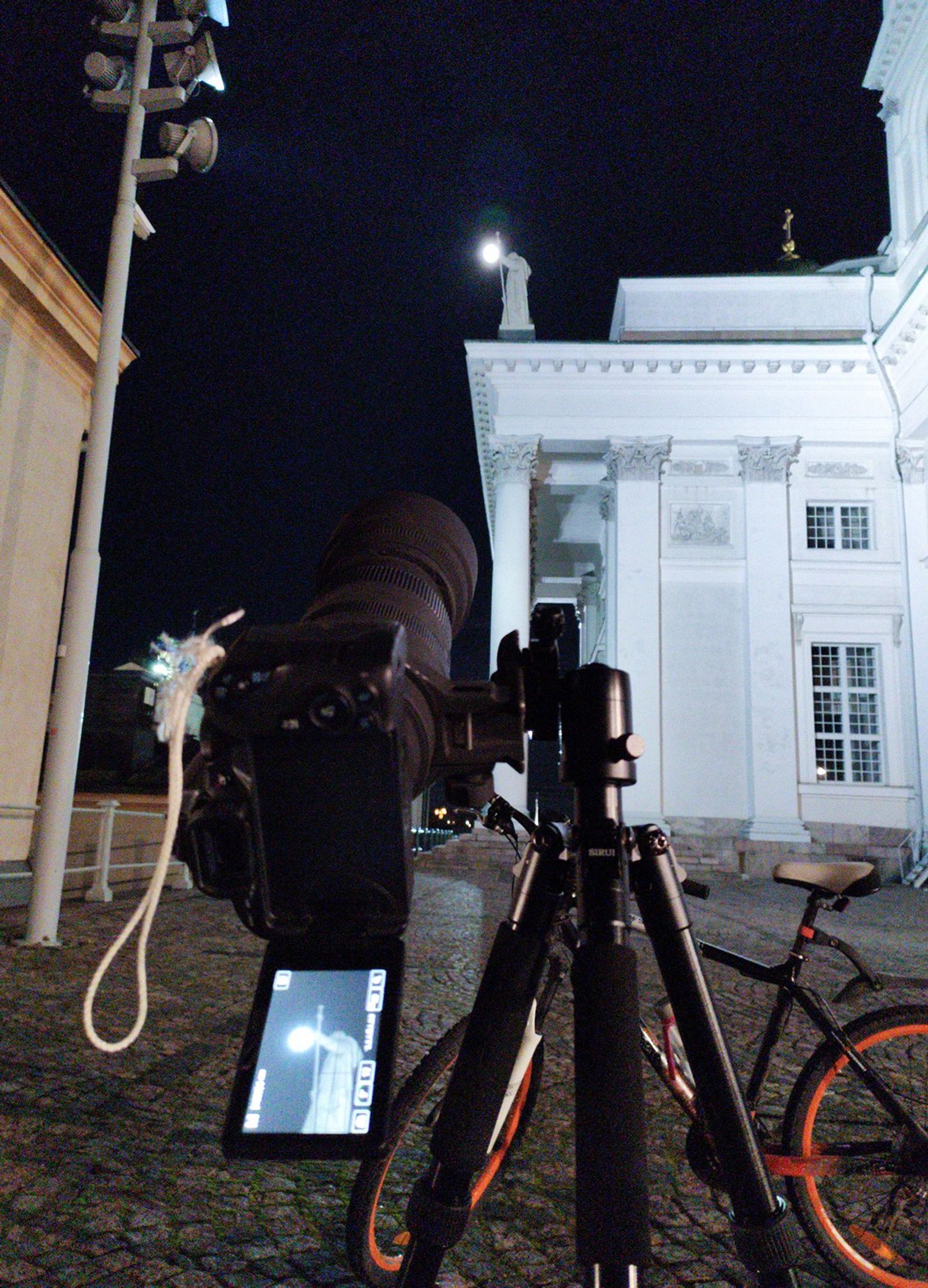 Kamera ottamassa kuvaa teleobjektiivilla kirkon patsaasta, kameran takana näkyy Tuomiokirkko