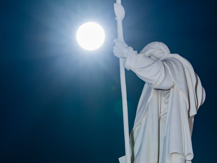 Sauvaa kädessä pitävä Helsingin Tuomiokirkon patsas, sekä valkoisena hehkuva kuu sen takana