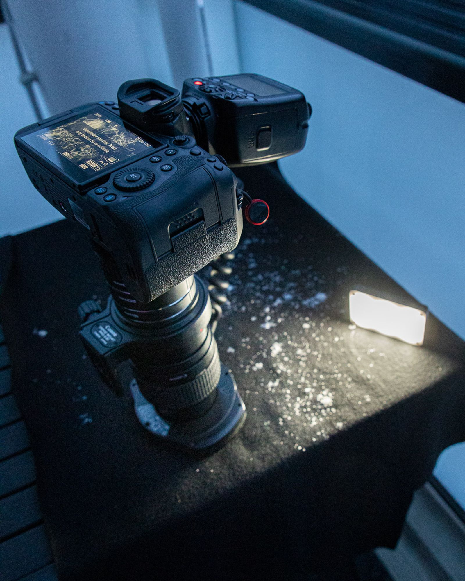 Kamera pitkällä makro-objektiivilla lumisen liinan päällä, sekä rengassalama