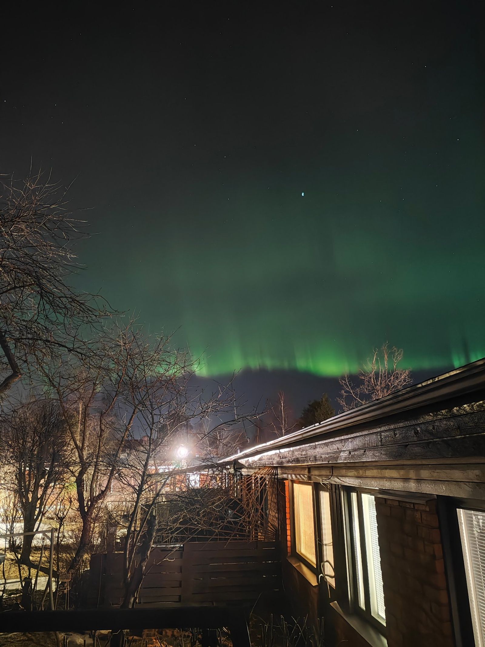 Revontulet oman katon päältä, erittäin valoisella taustalla.