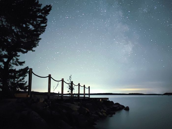 Tähtitaivas laiturin päällä järvimaisemassa. Kuvattu puhelimella.
