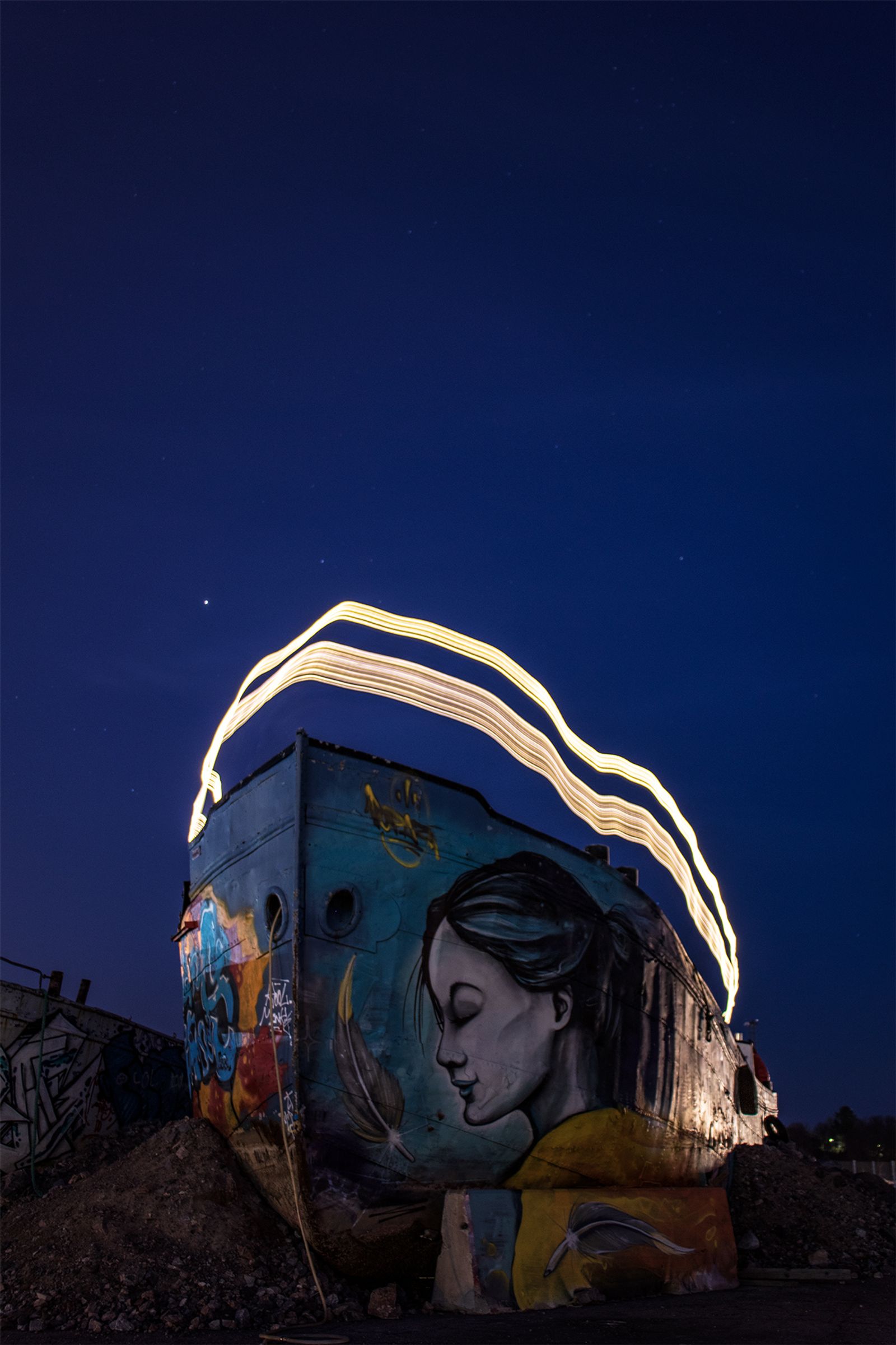 Graffiteilla täytetty laiva, jonka päällä on valolla maalattu kuvio pitkin laivan reunaa