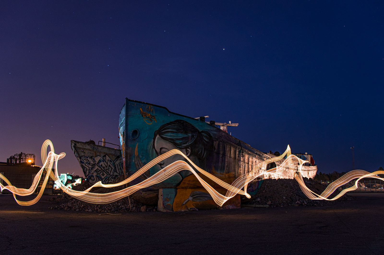 Valolla maalattu pitkän valoituksen kuvio hylätyn graffiteilla täytetyn laivan edessä yöllä