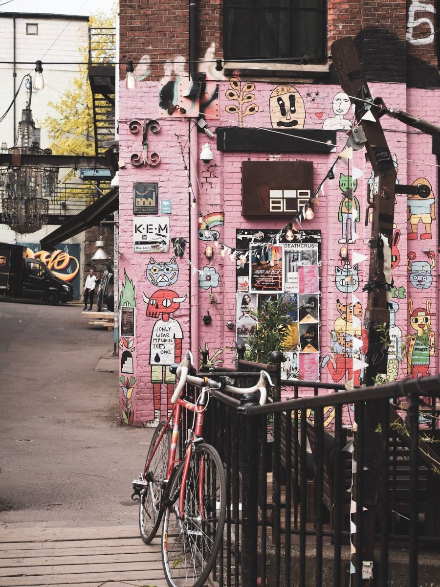 Kuva pinkistä seinästä, joka on täytetty julisteilla, sekä sen edessä olevasta polkupyörästä.