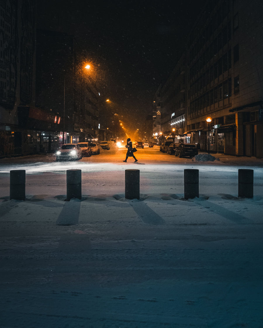 Nainen kävelee lumisateessa kaupungissa